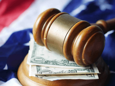 Gavel resting on dollar bills atop a folded American flag